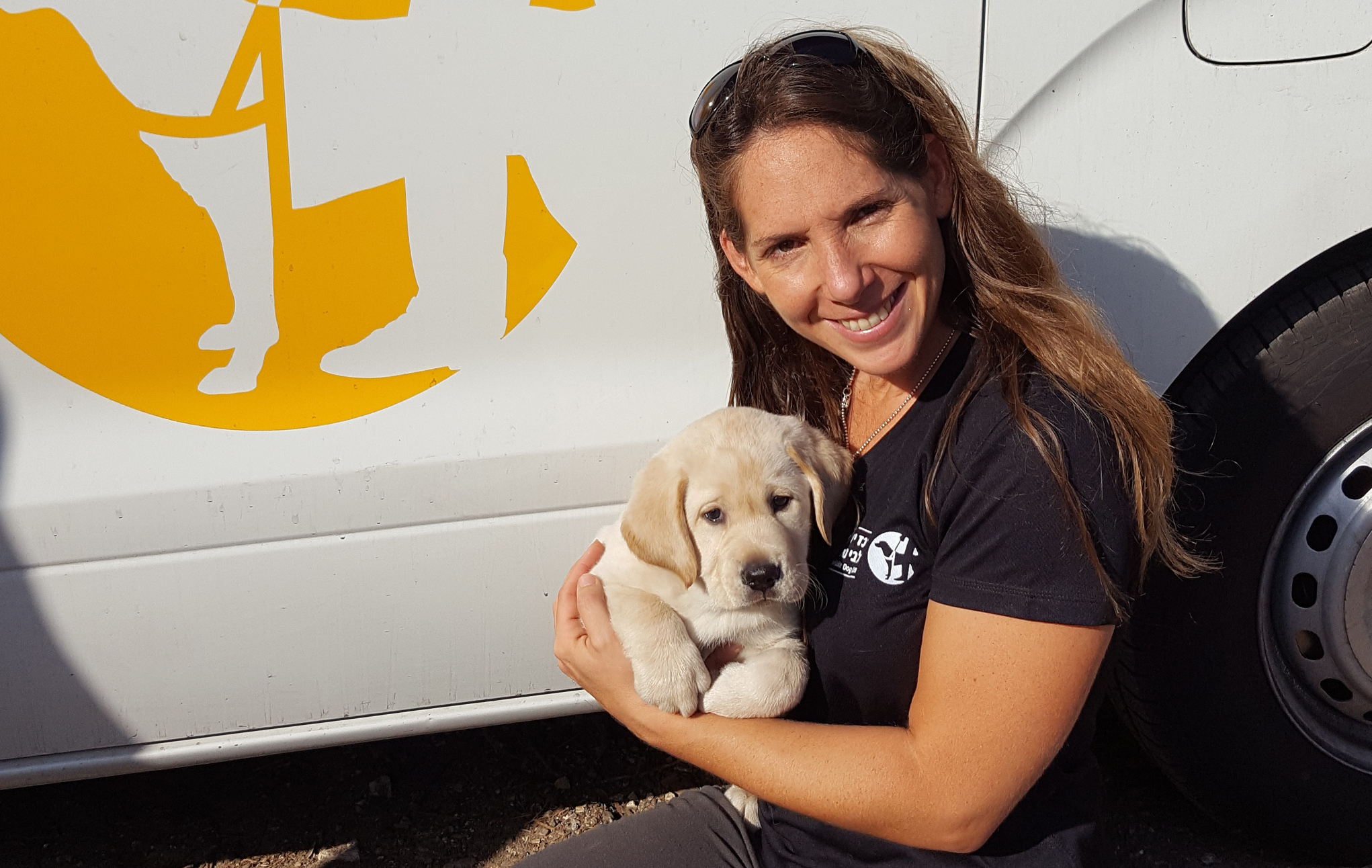 woman with puppy in front of IGDC van